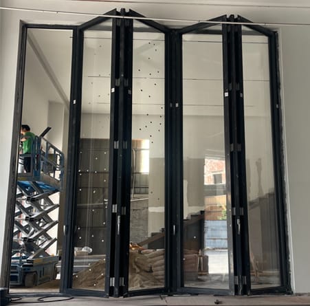 Full-width bi-fold door panels stacked to one side during installation