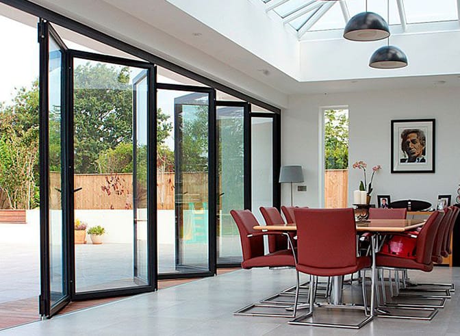80KSBG heavy-duty bi-fold doors folded open beside a dining room